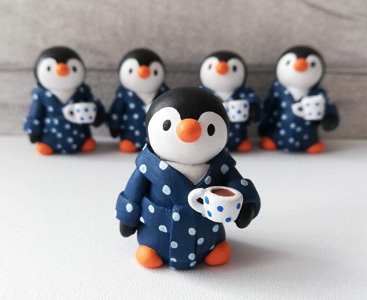 Penguin collectable by Kate Elford. Pottery penguins in dressing gowns, with a cup of tea