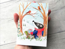 Load image into Gallery viewer, A badger and robins in the snow notebook shown in a hand to show the size