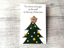 Load image into Gallery viewer, A cute gold smiling star mini enamel pin. It is displayed on a small white rectangular backing card which has a picture of a green Christmas tree. The wording at the top of the card reads you shine as bright as the star at the top of the tree. Designed by Kate Elford