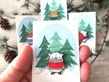 Load image into Gallery viewer, Cute polar bear in a red jumper enamel pin and matching stripey socks. It is on a backing card with three pine trees printed on it
