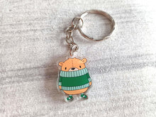 Load image into Gallery viewer, Recycled acrylic cute mini, light brown bear keyring. The bear is wearing a big dark green jumper which sits just under his nose and he is wearing matching green stripey socks