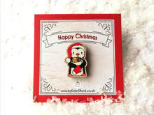 Load image into Gallery viewer, Mini wooden Christmas pin. Penguin wearing a Santa hat and holding a Christmas stocking. The wording on the backing card reads Happy Christmas