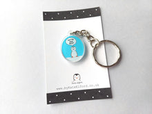 Load image into Gallery viewer, Mini oval recycled acrylic keyring. The design is a little penguin on a light blue background with a speech bubble saying you're the best. It is displayed on a small black and white backing card