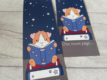 Load image into Gallery viewer, Guinea pig bookmarks. The picture shows that the two side are the same. It is a ginger and white guinea pig sat reading on a book. There is the words one more page at the bottom of the bookmark