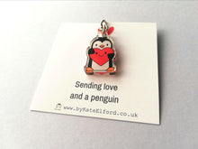 Load image into Gallery viewer, A mini recycled acrylic penguin keyring. The penguin is holding a bright red heart which has a happy smiling face. It is displayed on a small white square backing card with the wording sending love and a penguin.