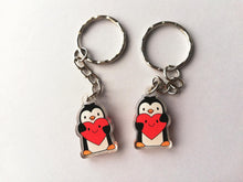 Load image into Gallery viewer, Mini recycled acrylic penguin keyrings. The penguins are holding hearts which have smiley faces.  It is the same design on both sides.