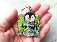 Load image into Gallery viewer, Penguin and potted house plants recycled acrylic hanger. Held in the palm of a hand as a size guide