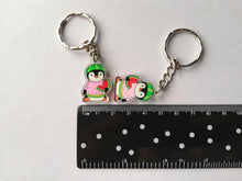 Load image into Gallery viewer, Watermelon penguin keyrings next to a small ruler as a size guide. They measure approximately 3cm including the acrylic loop