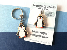 Load image into Gallery viewer, A wooden penguin keyring on a backing card with the wording the penguin of positivity wants to tell you, you are the best. Just keep being the amazing person you are