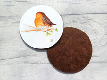 Load image into Gallery viewer, A round coaster with the image printed on the coaster of a watercolour fluffy robin sat on a branch with a few leaves and one leaf falling. The background is plain white. There is a second coaster to show the back is plain brown