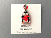 Load image into Gallery viewer, A mini recycled acrylic penguin keyring. A penguin is holding a red heart which has a smiley face. Displayed on a square backing card with the wording sending love and a penguin.