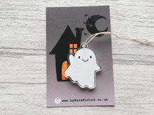 Load image into Gallery viewer, Recycled acrylic ghost hanger waving. It has a cute smiling face and is displayed on a backing card that is dark grey with a black house and moon silhouette