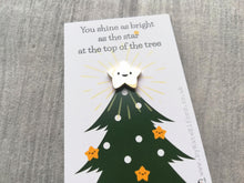 Load image into Gallery viewer, Mini gold cute smiling star enamel pin. It is displayed on a small white rectangular backing card which has a picture of a green Christmas tree. The wording at the top of the card reads you shine as bright as the star at the top of the tree. Designed by Kate Elford