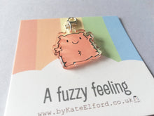 Load image into Gallery viewer, A fuzzy feeling. A little peachy orange happy, fuzzy looking character. It has a clip to be used as a charm or stitch marker