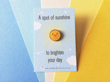 Load image into Gallery viewer, A mini round enamel pin. It is yellow glitter colour with a happy face. The words on the blue backing card read a spot of sunshine to brighten your day