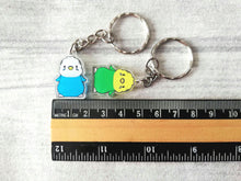 Load image into Gallery viewer, Budgie keyrings next to a ruler for a, size guide