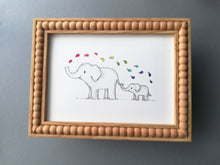 Load image into Gallery viewer, A photo to show that the elephants and rainbow drops print fits into a standard size 7x5 frame