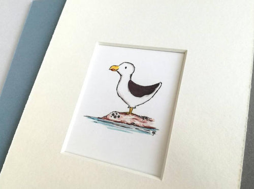 Seaside seagull print, coastal theme, bathroom print, grey, blue or white mount. Little seagull is stood on a rock with barnacles, and the sea is around the rock. A great picture for a bathroom, or a coastal theme
