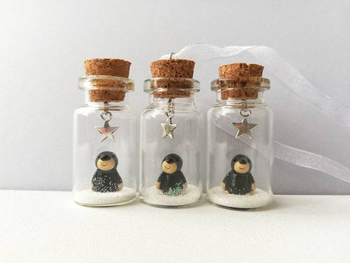 Miniature mole decoration. Little pottery hedgehog in a glass bottle. Christmas mole, snow and star ornament