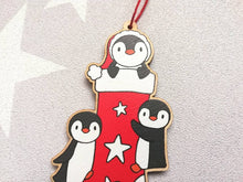 Load image into Gallery viewer, Penguin Christmas stocking decoration. Wooden penguins Christmas tree ornament. Red and white stocking with stars, eco friendly wood