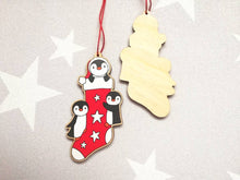 Load image into Gallery viewer, Penguin Christmas stocking decoration. Wooden penguins Christmas tree ornament. Red and white stocking with stars, eco friendly wood