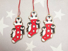 Load image into Gallery viewer, Penguin Christmas stocking decoration. Wooden penguins Christmas tree ornament. Red and white stocking with stars, eco friendly wood
