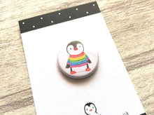 Load image into Gallery viewer, Mini button badge close up. A small round badge with a white background. The picture is a black and white penguin wearing a rainbow colour striped jumper