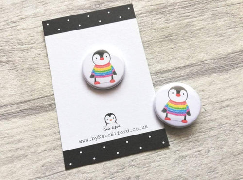 Mini button badge. A small round badge with a white background. The picture is a black and white penguin wearing a rainbow colour striped jumper