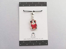 Load image into Gallery viewer, Little clear acrylic guinea pig stitch marker. It is made from recycled acrylic, the guinea pig is wearing a red hat, jumper and scarf
