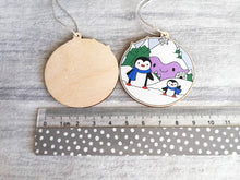 Load image into Gallery viewer, Penguin Christmas decoration. Snowy purple mountains small wooden ornament. Ethically sourced wood. Cute penguins Christmas tree ornaments.