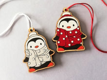 Load image into Gallery viewer, Two wooden penguin Christmas decorations. They are wearing bobble hats and spotty scarves. One is wearing red, the other grey.