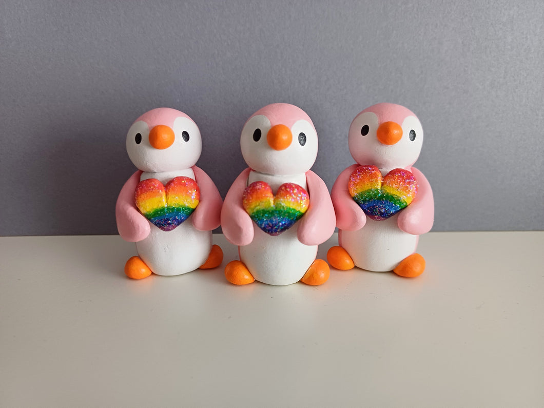 Pink penguin holding a rainbow heart