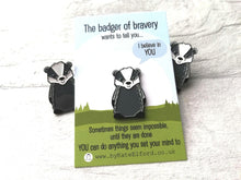 Load image into Gallery viewer, Three cute badger enamel pins with one on a backing card and two badgers peeking out at the sides. The backing card has the wording the badger of bravery wants to tell you I believe in you. Sometimes things seem impossible until they are done. You can do anything you set your mind to
