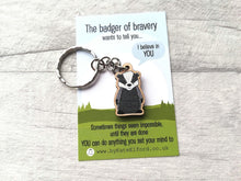 Load image into Gallery viewer, A miniature wooden badger keyring. The backing card has the wording the badger of bravery wants to tell you I believe in you. Sometimes things seem impossible until they are done. You can do anything you set your mind to
