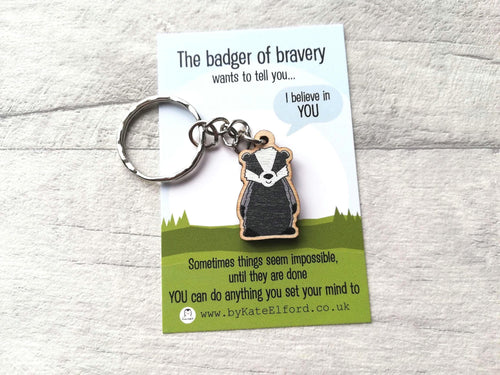 A miniature wooden badger keyring. The backing card has the wording the badger of bravery wants to tell you I believe in you. Sometimes things seem impossible until they are done. You can do anything you set your mind to