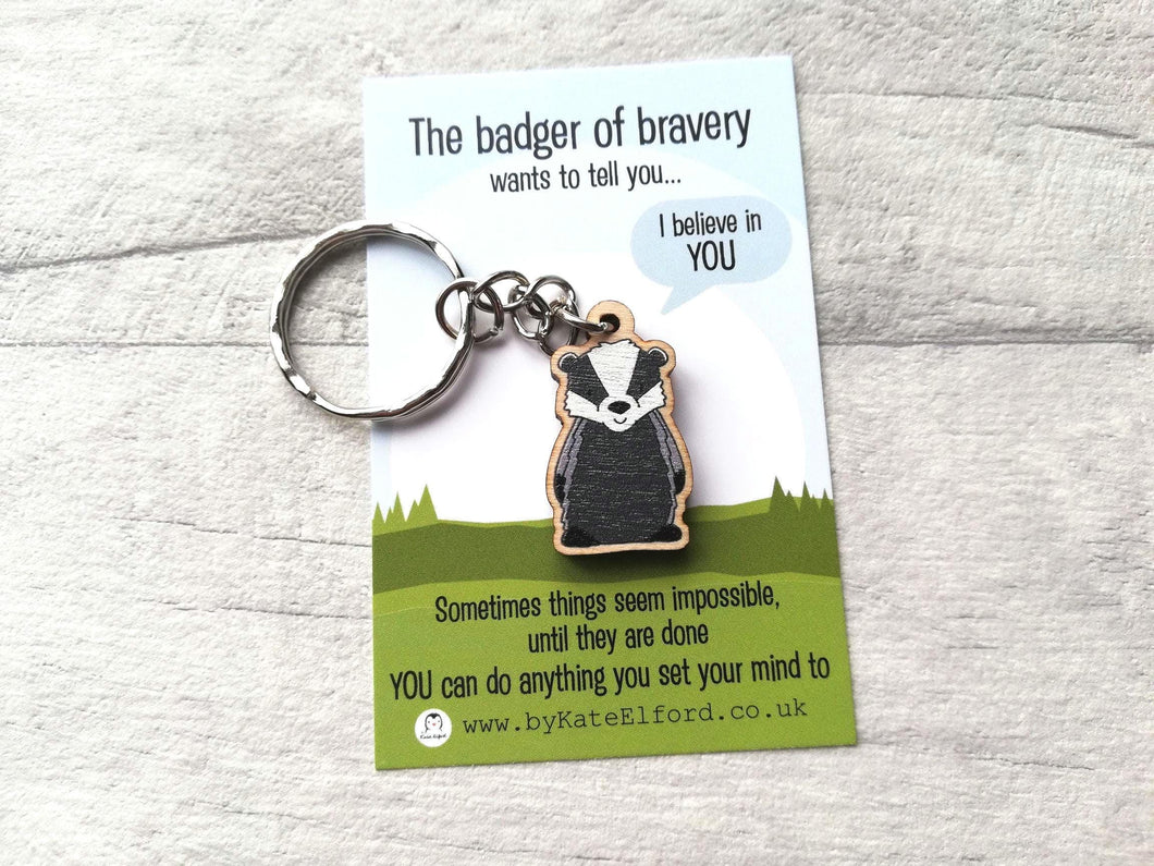 A miniature wooden badger keyring. The backing card has the wording the badger of bravery wants to tell you I believe in you. Sometimes things seem impossible until they are done. You can do anything you set your mind to