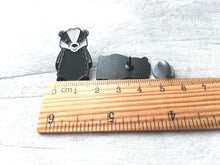 Load image into Gallery viewer, A badger enamel pin next a ruler as a size guide
