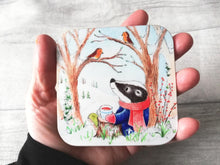 Load image into Gallery viewer, Badger sat under a tree with two robins. Winter countryside design with snowdrops. Square glossy small coaster
