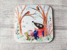 Load image into Gallery viewer, Badger sat under a tree with two robins. Winter countryside design with snowdrops. Square glossy small coaster
