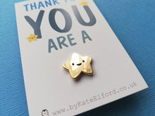Load image into Gallery viewer, Close up of a miniature gold happy star enamel pin. It is on a small white rectangular backing card with the wording thank you you are a at the top and the star pin is attached at the bottom, to send the message you you are a star
