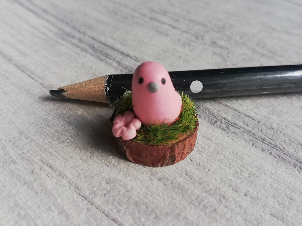 Miniature pink bird on wood base