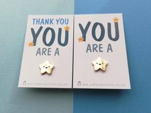 Load image into Gallery viewer, Gold star enamel pin. The tiny star has five points and a happy face. It is on a mini white rectangular backing card with the wording thank you you are a at the top and the star pin is attached at the bottom. The second backing card has the wording you are a with the same design star displayed underneath
