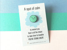 Load image into Gallery viewer, A spot of calm enamel pin. A cute blue glittery round pin with a happy face. The wording on the card says A spot of calm to remind you that in all the chaos to take time to breathe you&#39;re doing great
