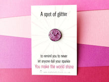 Load image into Gallery viewer, A pink spot of glitter enamel pin with a happy face. The words on the card reads a spot of glitter to remind you to never let anyone dull your sparkle. You make the world shine.
