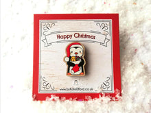 Load image into Gallery viewer, Mini wooden Christmas pin. Penguin wearing a Santa hat and holding a Christmas stocking. The wording on the backing card reads Happy Christmas
