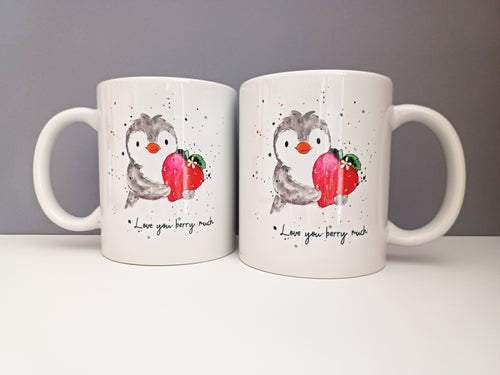 A mug with a penguin holding a strawberry and the wording I love you berry much. The photo shows both sides of the mug with a matching design 