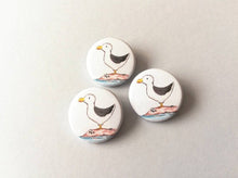 Load image into Gallery viewer, Three seagull badges. The gulls are stood on a rock by the sea with some barnacles on the rocks
