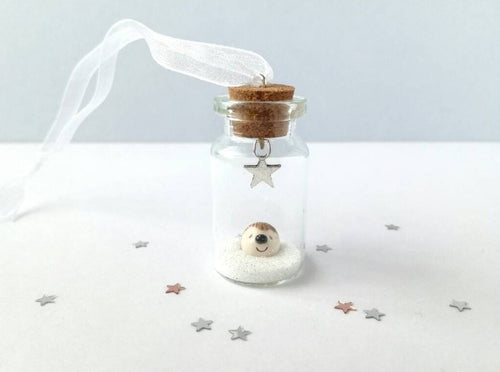 Miniature hedgehog decoration. Little pottery hedgehog in a glass bottle. Christmas hedgehog ornament