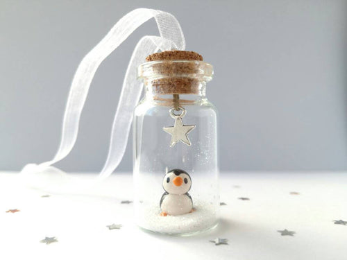 Miniature penguin decoration. Little pottery penguin in a glass bottle. Christmas penguin mini ornament