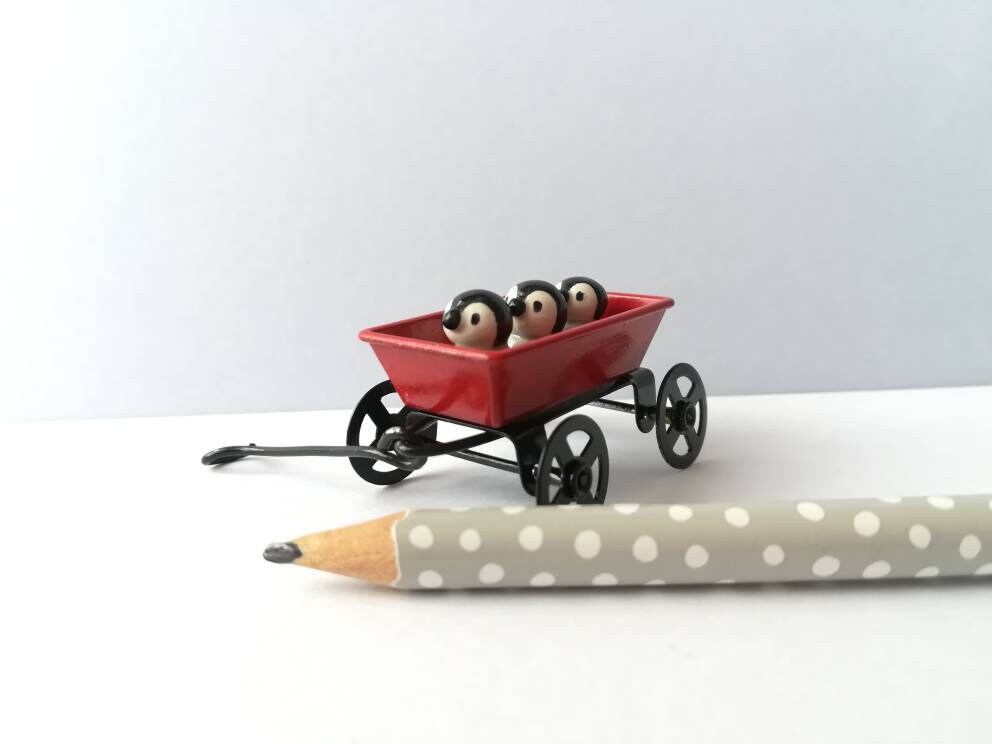 Miniature penguins in a cart. Little pottery penguin chicks in a red truck. Cute penguins